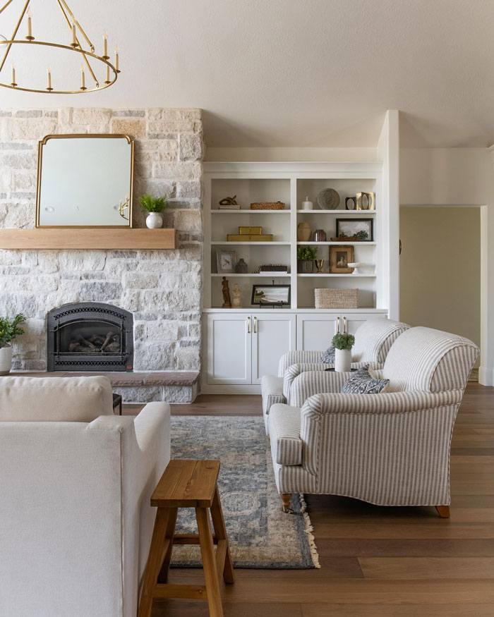White creamy interior farmhouse with striped sofas and white cupboard and fireplace White creamy interior farmhouse with striped sofas and white cupboard and fireplace