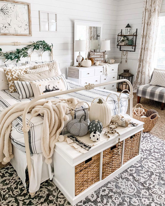 White decor bed with white pillows and striped sheets and with white cupboard and pumpkins White decor bed with white pillows and striped sheets and with white cupboard and pumpkins