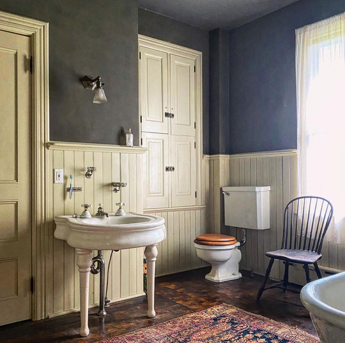 Vintage rug with white sink and toilet with dark brown wooden floors Vintage rug with white sink and toilet with dark brown wooden floors