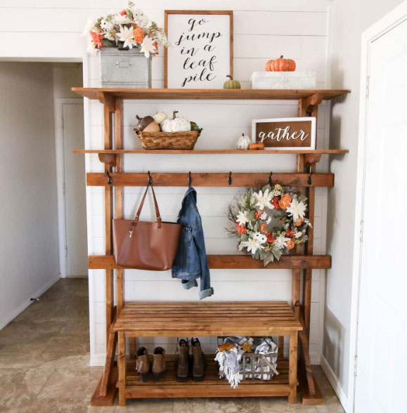 A wooden hall tree with clothing items decorated with pumpkins and flowers A wooden hall tree with clothing items decorated with pumpkins and flowers