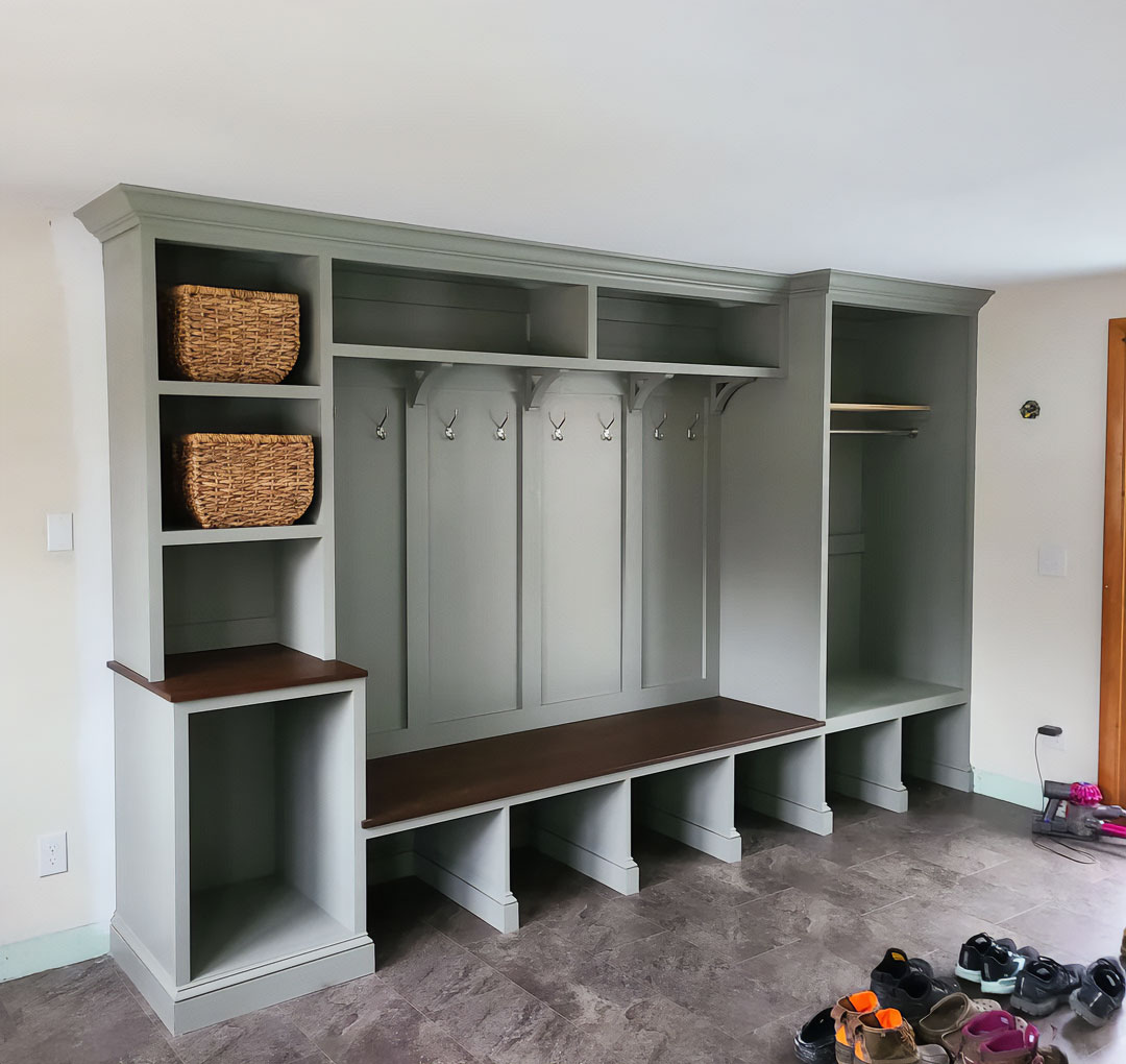 A wide grey hall tree with a bench and many storage nooks against a wall A wide grey hall tree with a bench and many storage nooks against a wall