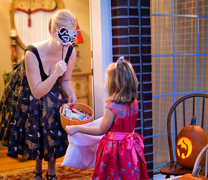 Trick or treats woman giving candy to girl for Halloween