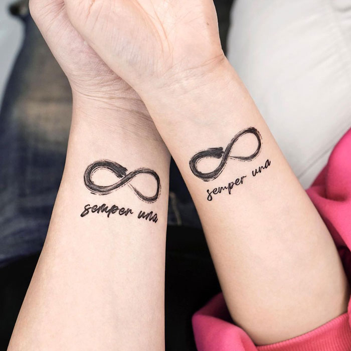 Infinity tattoos on wrists with "semper una" text, showcasing eternal creativity.