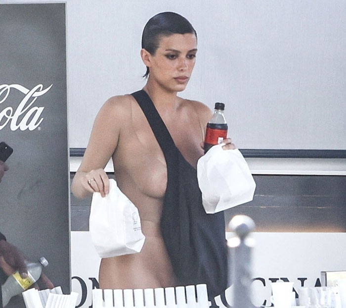 Bianca Censori in a daring outfit, holding a drink and fast food bag.