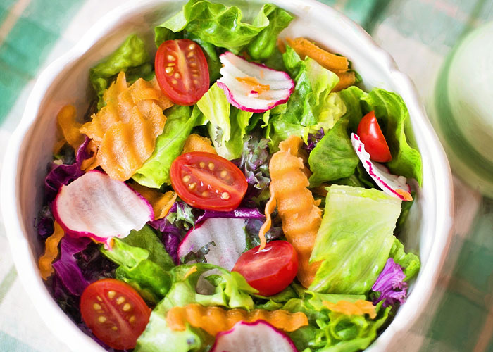 Fresh salad with lettuce, cherry tomatoes, carrots, and radish slices showcasing restaurant green flags for quality food.