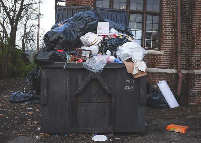 Overflowing trash outside a building illustrating poor restaurant green flags to avoid when choosing where to eat
