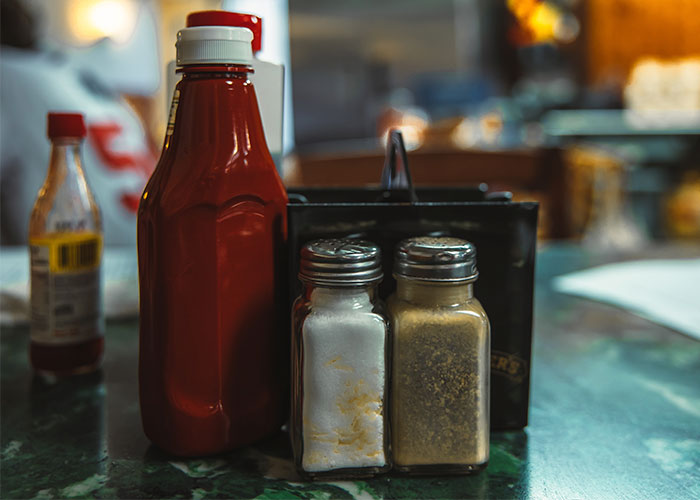 Condiments including ketchup, salt, and pepper on a table indicating restaurant green flags for dining.