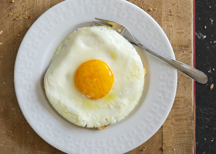 Sunny side up egg on a white plate with fork, highlighting restaurant green flags that indicate quality dining spots.