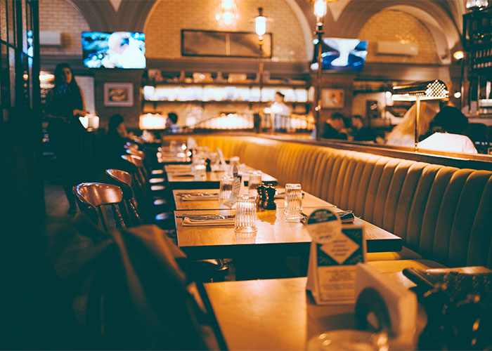 Cozy restaurant interior with warm lighting and neatly set tables showing restaurant green flags for diners.