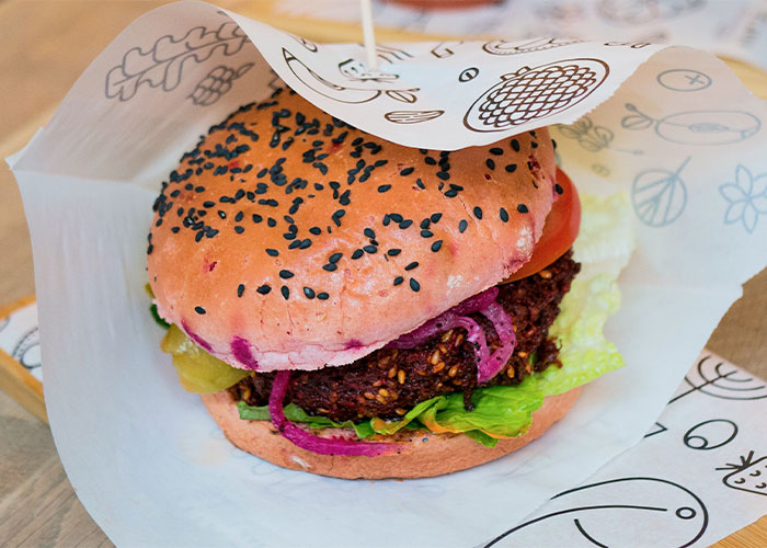 Close-up of a fresh burger with sesame bun and vegetables, highlighting restaurant green flags to eat there confidently.