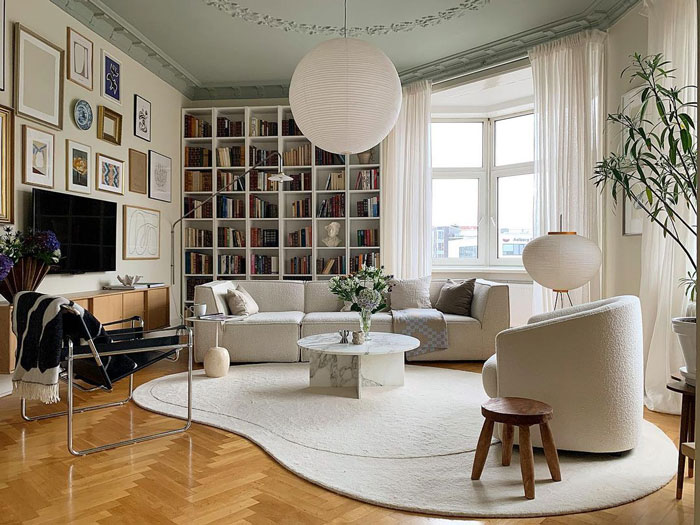 Living room ideas with a light green ceiling, white couch, bookshelves wall, and modern cozy interior design.