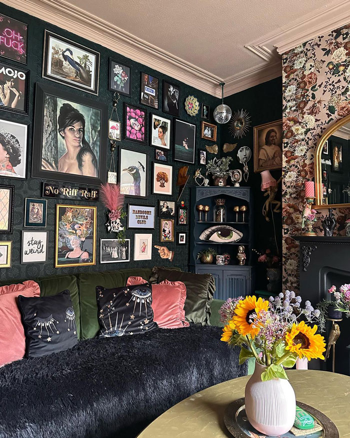 Black wall filled with eclectic wall art above a cozy sofa, featuring living room ideas and designer insights.
