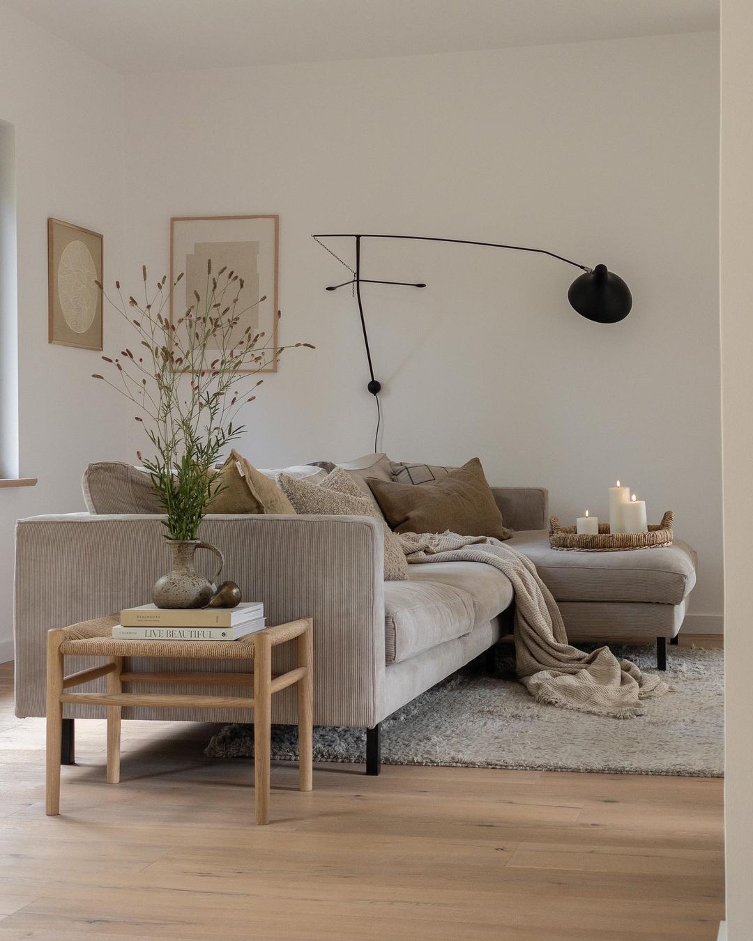 Scandinavian style living room with white walls, beige L-shaped couch, cozy pillows, and minimalist decor for interior refresh.
