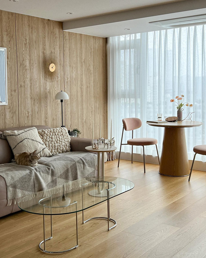 Beige living room with wooden walls, cozy couch, glass coffee table, and dining area showcasing living room ideas and design insights.