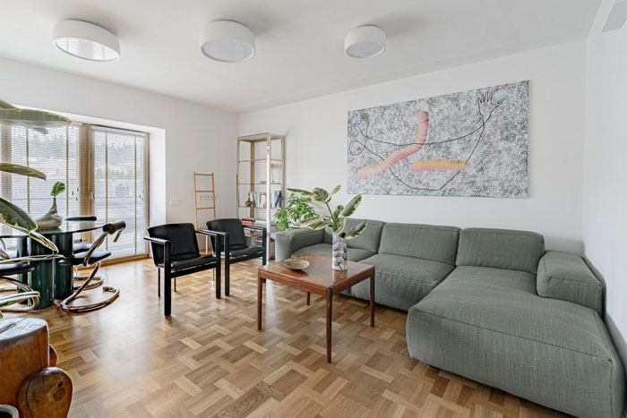 Living room with large gray L-shaped couch and modern painting, showcasing living room ideas and designer insights.