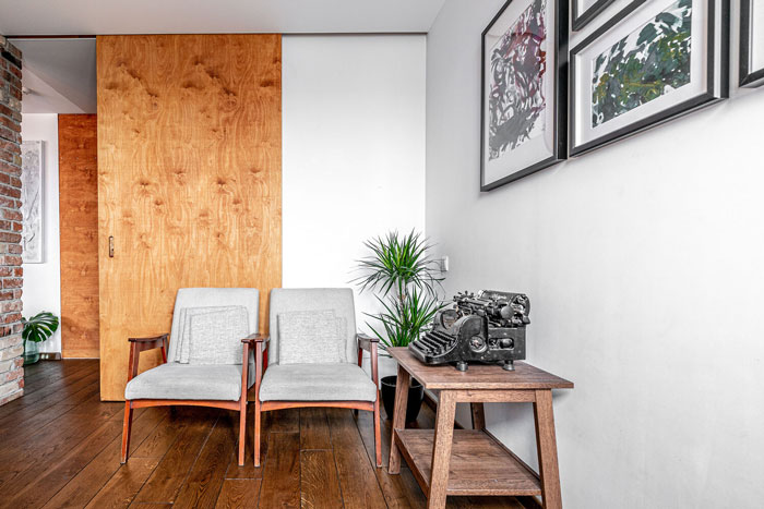 Living room ideas featuring two armchairs, wooden flooring, wall art, and decorative plants in a modern interior space.