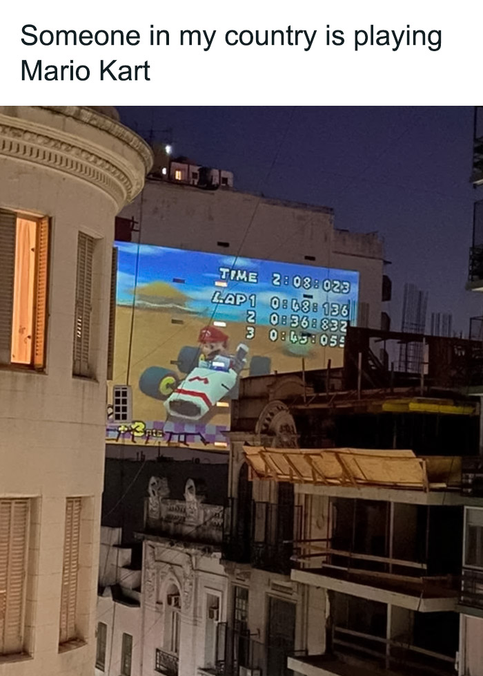 Mario Kart projected on city building at night, showcasing funny Mario memes.