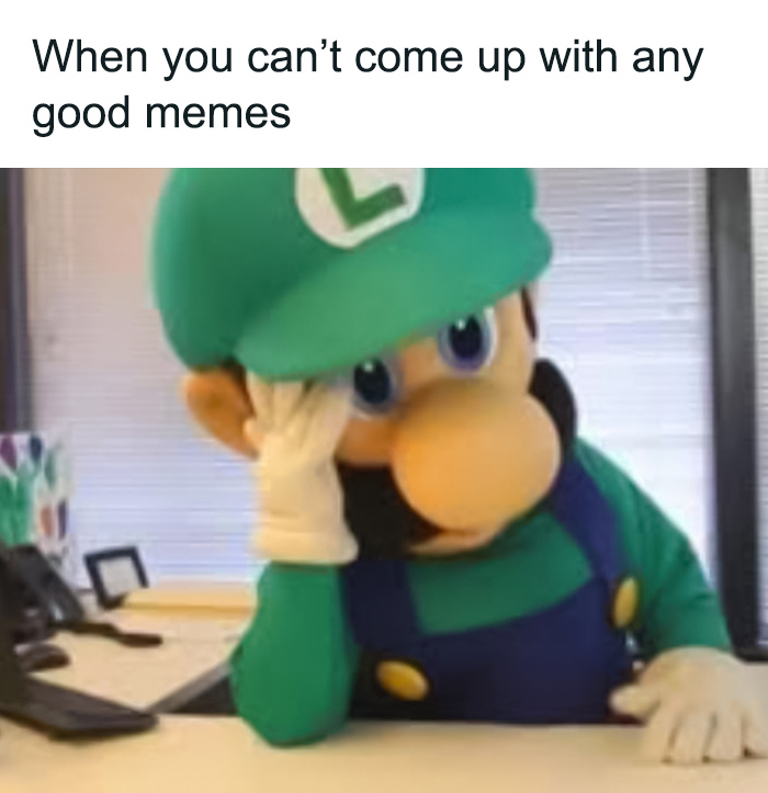 Luigi in his green outfit at a desk, looking frustrated with his hand on his face.
