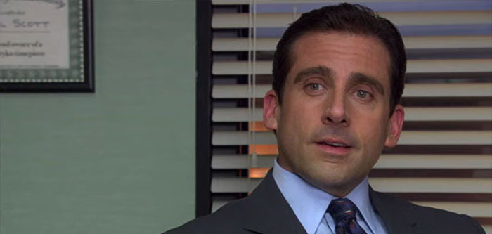 Michael Scott talking in his office wearing a suit and tie, showcasing iconic quotes from the best boss ever.