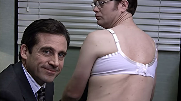 Michael Scott and Dwight in a humorous scene demonstrating bra removal, showcasing iconic Michael Scott quotes about boss moments.