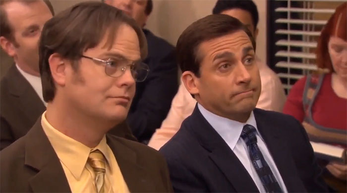 Michael Scott and Dwight attentively listening in a meeting scene illustrating memorable Michael Scott quotes about leadership.