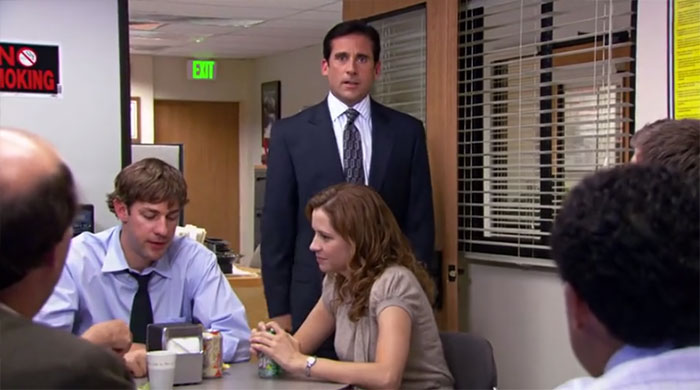 Michael Scott standing in the conference room with employees, showcasing the best boss ever vibe from The Office.