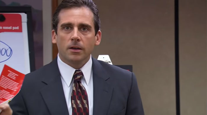 Michael Scott holding a card in an office setting, showcasing iconic Michael Scott quotes as a memorable best boss moment.
