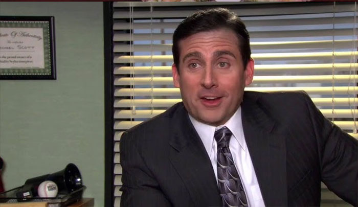 Michael Scott talking in his office, wearing a suit and tie, showcasing iconic Michael Scott quotes as best boss ever.