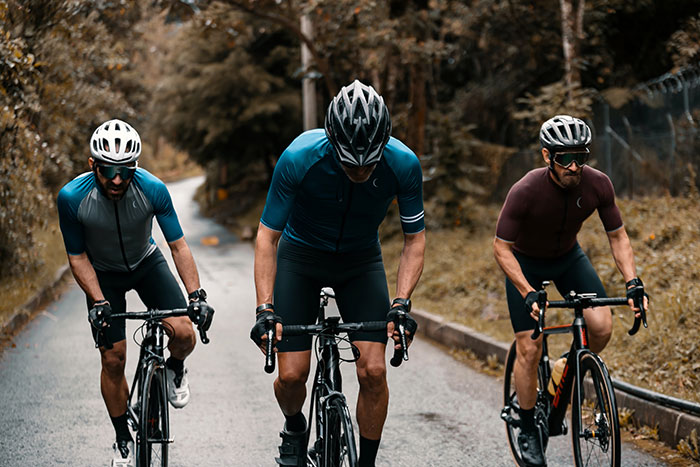 Three men wearing blue and red shirts cycling on a forest road, capturing dynamic energy fit for amazing music facts.