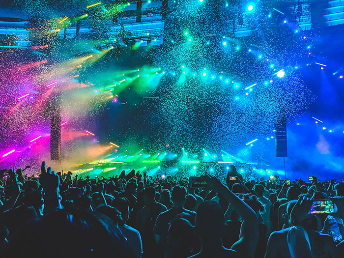 Concert crowd enjoying a vibrant show with colorful lights and glitter, capturing amazing and bizarre music moments live.