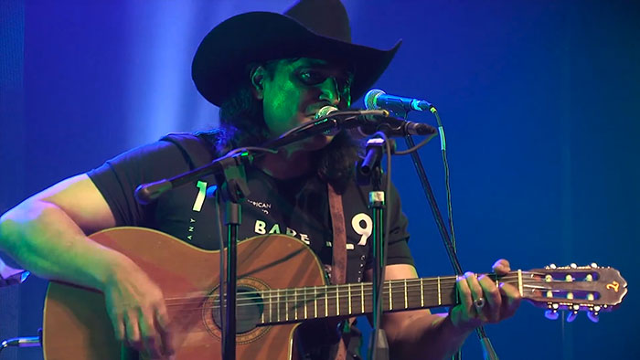 Bobby Cash performing live on stage with an acoustic guitar, highlighting amazing and bizarre music facts.