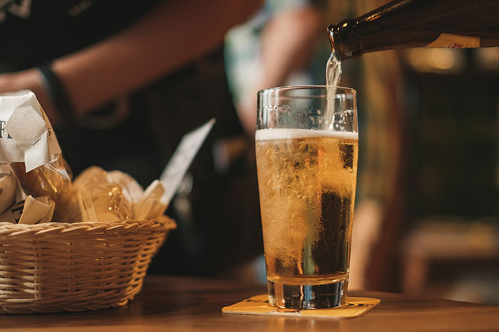 Man pouring beer into a glass at a bar, illustrating a relaxing moment linked to amazing and bizarre music facts.