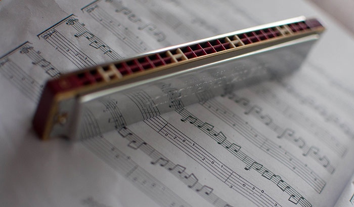 Harmonica resting on a music sheet, illustrating amazing and bizarre music facts to soothe your ears.