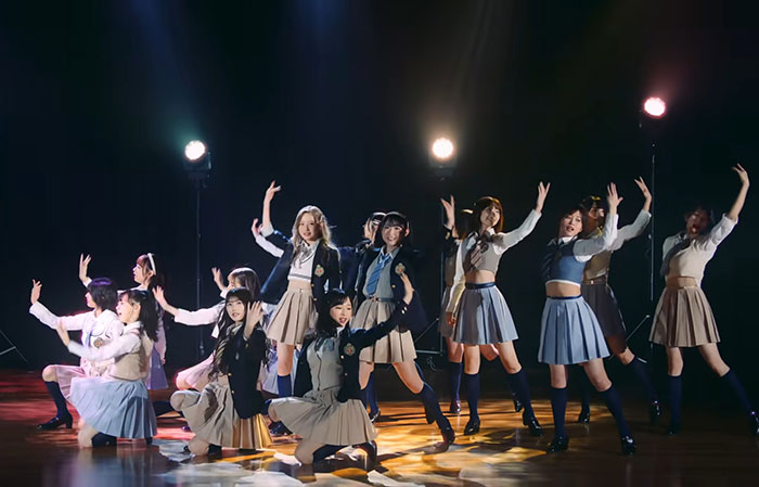 AKB48 band dancing and singing on stage with bright lights, showcasing amazing music moments to soothe your ears.