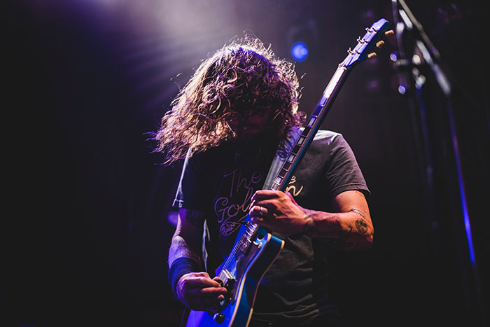 Rock guitarist with long hair playing electric guitar on stage, illustrating amazing and bizarre music facts.