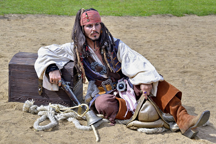 Man dressed as pirate near a chest, illustrating bizarre music facts to soothe your ears with a unique costume scene.