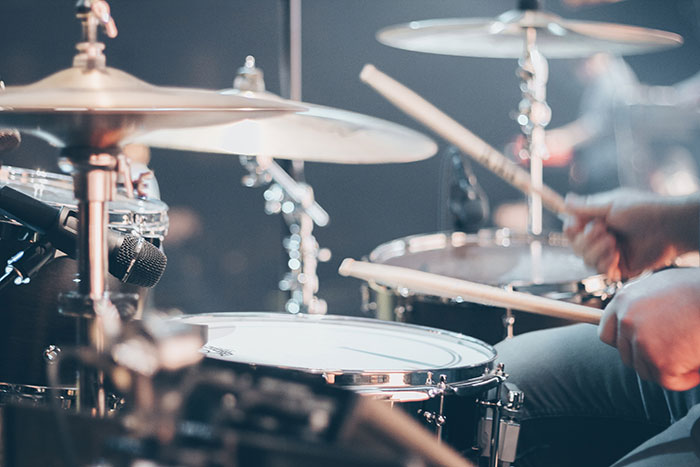 Man playing drums in a live music setting, showcasing rhythm and beats with amazing music facts inspiration.