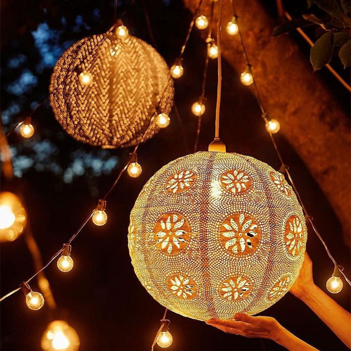 Person holding big lantern hanged on tree Person holding big lantern hanged on tree