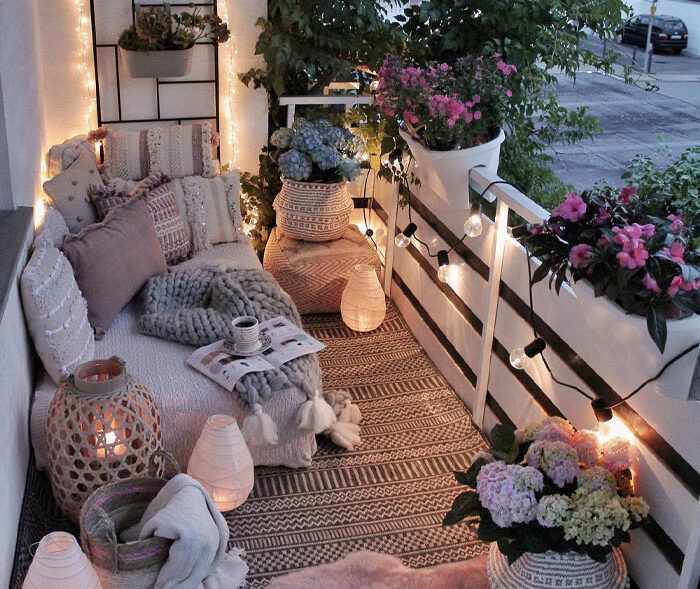 Bohemian balcony with furniture pillows sheets rug flowers and string lights Bohemian balcony with furniture pillows sheets rug flowers and string lights