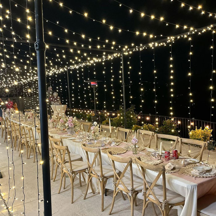 Outdoor light canopy with tables with white sheets and wooden chairs Outdoor light canopy with tables with white sheets and wooden chairs