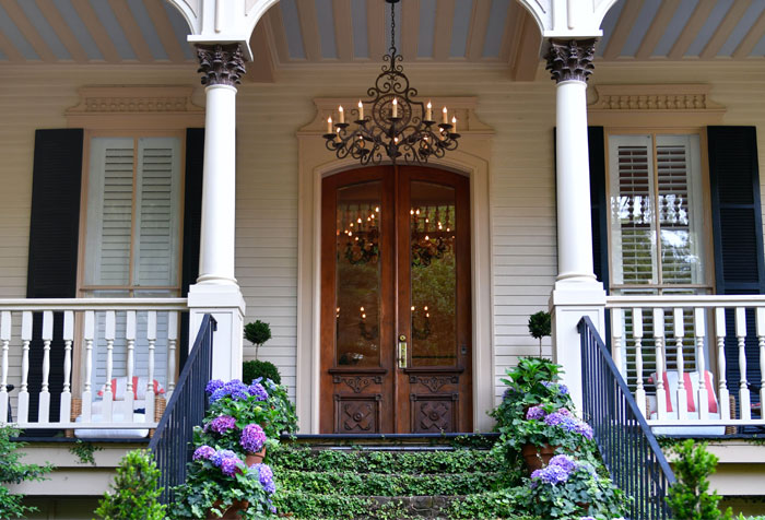a large white house with a bunch of flowers on the steps and porch with chandeliers a large white house with a bunch of flowers on the steps and porch with chandeliers