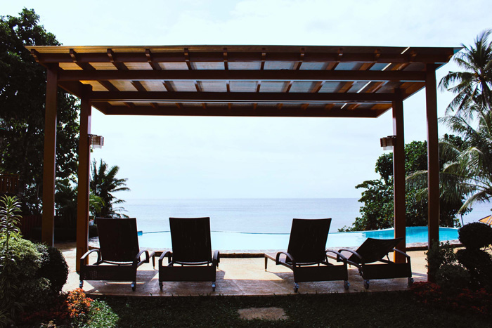 Pergola built on a beachfront with lounge chairs facing the ocean, showcasing a stunning backyard outdoor living space.