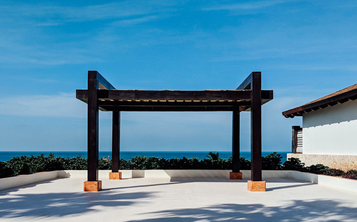 Modern wooden pergola with ocean view under clear blue sky, showcasing stunning backyard pergola ideas for outdoor living.