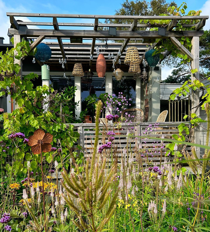 Safari pergola surrounded by colorful flowers and greenery enhancing a stunning backyard outdoor space.