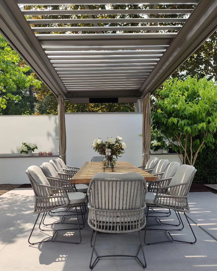 Wooden pergola above outdoor dining table and chairs creating a stunning backyard seating area with greenery.