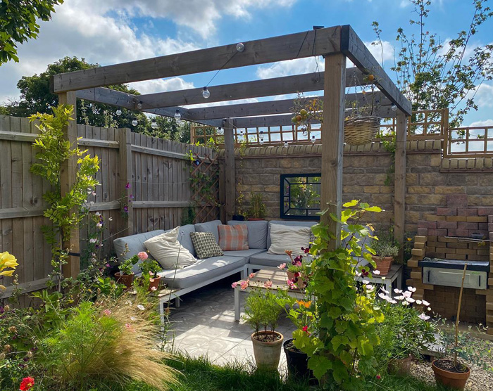 Wooden garden pergola with outdoor seating area and plants creating a stunning backyard relaxation space.