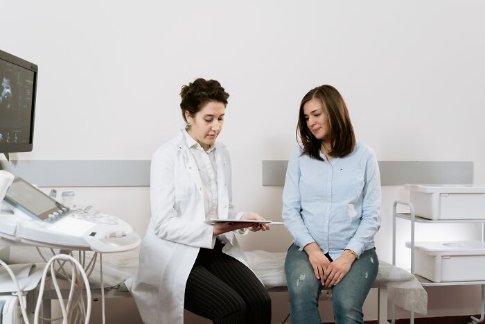 Doctor in a white coat consulting a female patient in a medical office, illustrating human stupidity concepts.