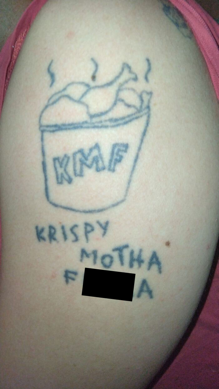 Tattoo of a chicken bucket with text "KMF" above "Krispy Motha F***a," illustrating a tattoo fail.