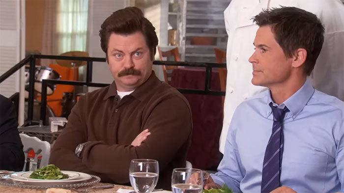 Ron Swanson sitting in a restaurant with crossed arms, representing Ron Swanson quotes about life.