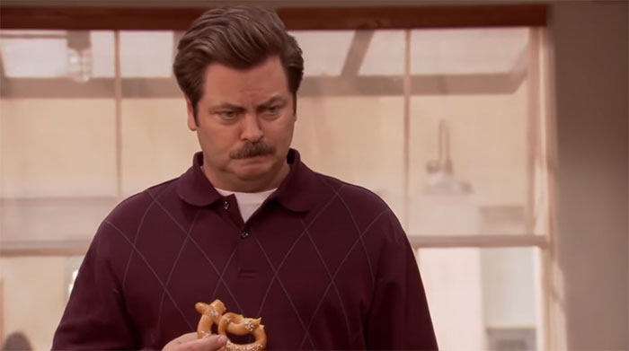 Ron Swanson eating a pretzel indoors, reflecting a moment that fits the Ron Swanson quotes on life theme.